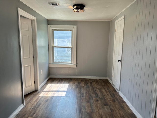 empty room with dark wood-type flooring and ornamental molding