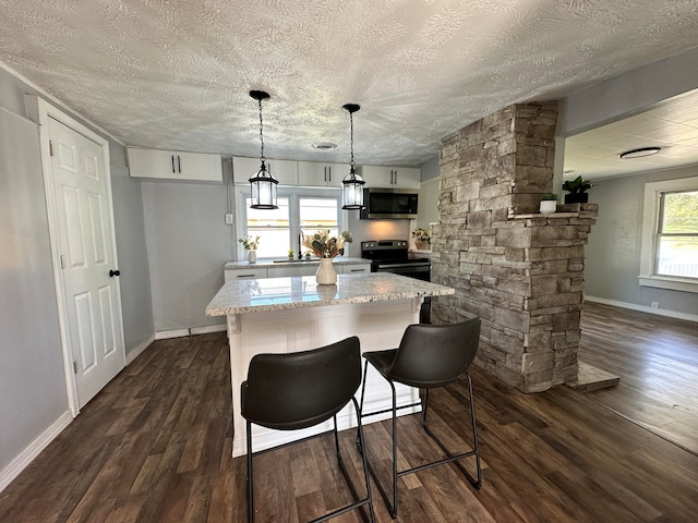 kitchen with a breakfast bar area, dark hardwood / wood-style flooring, a textured ceiling, and light stone counters