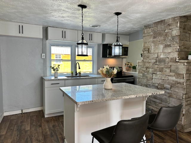 kitchen featuring white cabinets, sink, hanging light fixtures, and dark hardwood / wood-style flooring