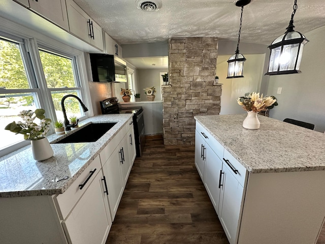 kitchen featuring an island with sink, pendant lighting, black electric range oven, dark hardwood / wood-style flooring, and ornate columns