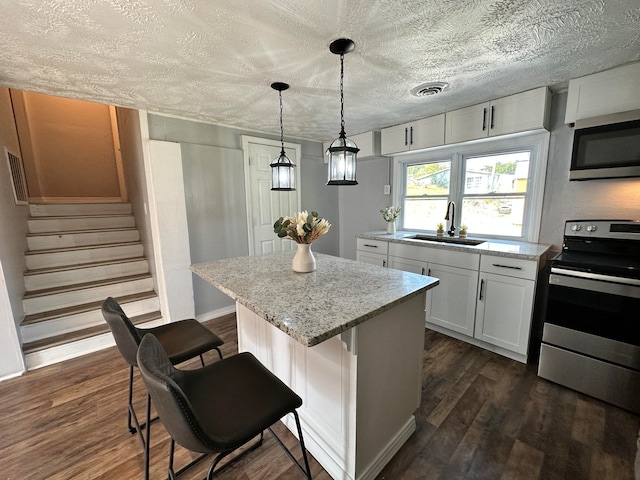 kitchen with a center island, sink, appliances with stainless steel finishes, white cabinetry, and dark hardwood / wood-style flooring