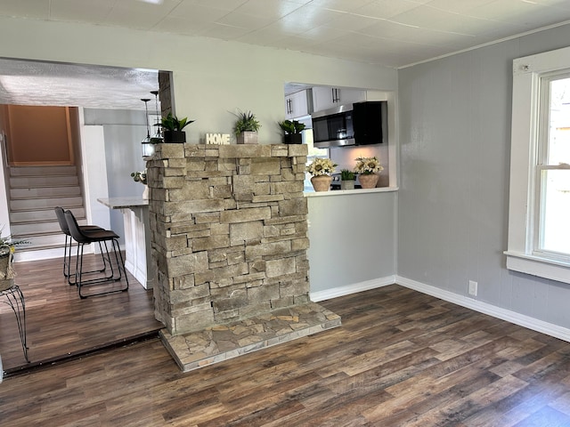 bar featuring dark hardwood / wood-style flooring and a healthy amount of sunlight