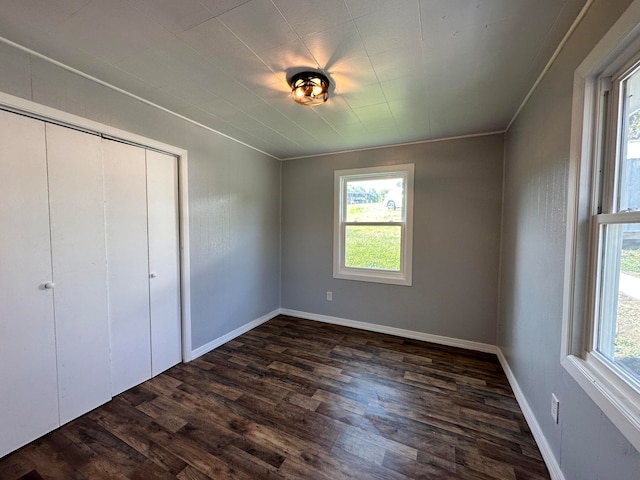 unfurnished bedroom with dark hardwood / wood-style floors, a closet, and multiple windows