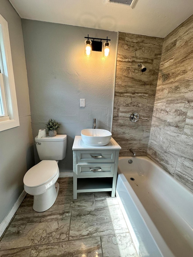 full bathroom with tile floors, tiled shower / bath, toilet, and vanity