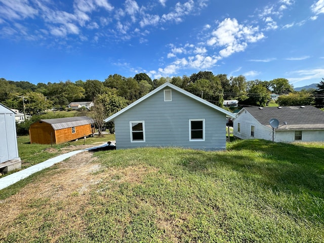 back of house featuring a yard and an outdoor structure