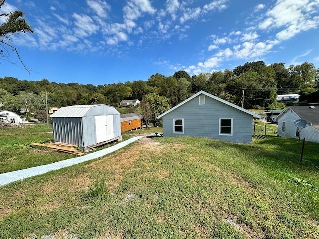 rear view of property with a storage unit and a yard