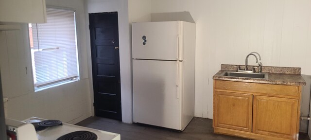 kitchen featuring stove, white fridge, dark wood-type flooring, and sink