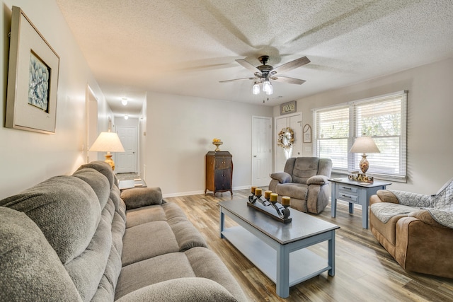 living room with light hardwood / wood-style floors, a textured ceiling, and ceiling fan