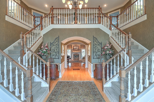 entrance foyer featuring an inviting chandelier, ornamental molding, light wood-type flooring, and a towering ceiling