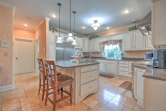 kitchen with built in refrigerator, a kitchen island, light tile flooring, and hanging light fixtures