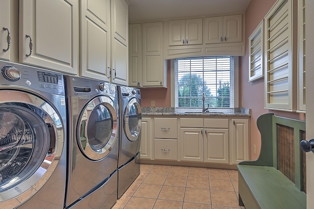 laundry area featuring washing machine and clothes dryer, sink, cabinets, and light tile floors