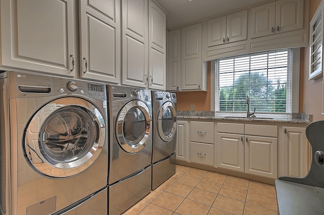 washroom featuring sink, independent washer and dryer, cabinets, and light tile flooring