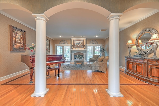 interior space featuring crown molding, decorative columns, and light wood-type flooring