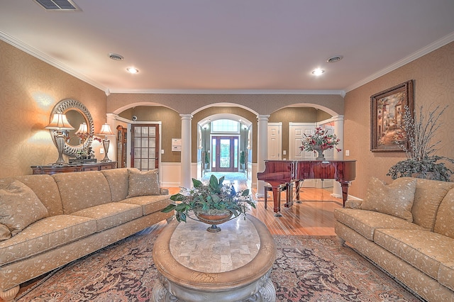 living room featuring decorative columns, ornamental molding, and hardwood / wood-style flooring