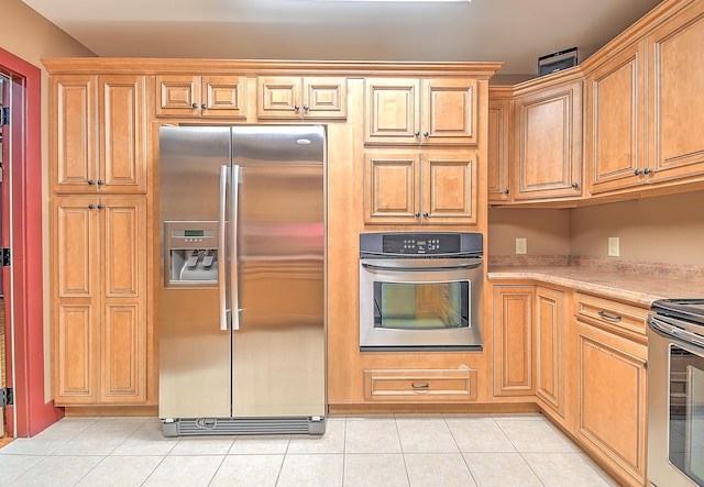 kitchen with light stone counters, light tile floors, and stainless steel appliances