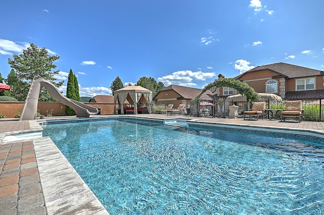 view of swimming pool with a water slide and a patio