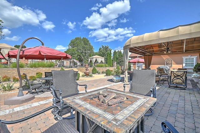 view of patio / terrace with a gazebo, ceiling fan, and a fire pit