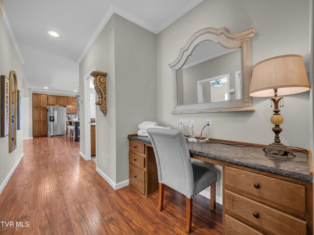 home office with built in desk, hardwood / wood-style flooring, and ornamental molding