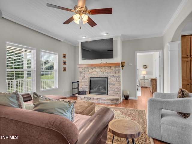 living room featuring light hardwood / wood-style flooring, ceiling fan, ornamental molding, and a fireplace