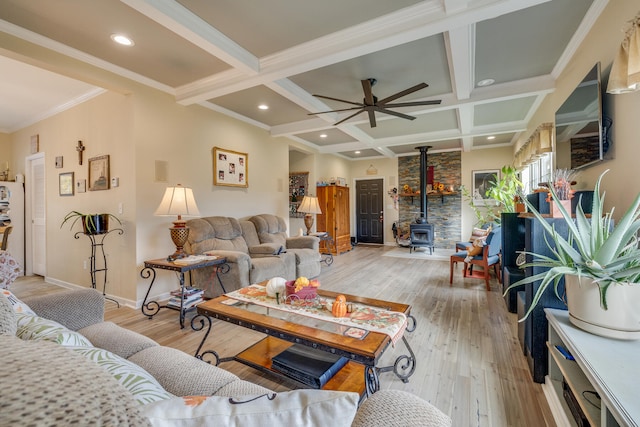 living room featuring ceiling fan, a wood stove, beamed ceiling, light hardwood / wood-style flooring, and coffered ceiling