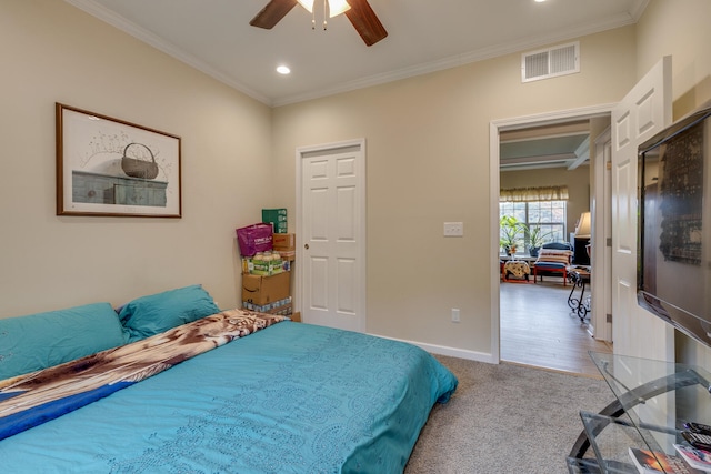 carpeted bedroom with ornamental molding and ceiling fan