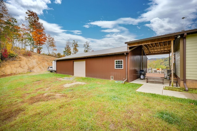 rear view of property with a patio, a lawn, an outdoor structure, and a garage