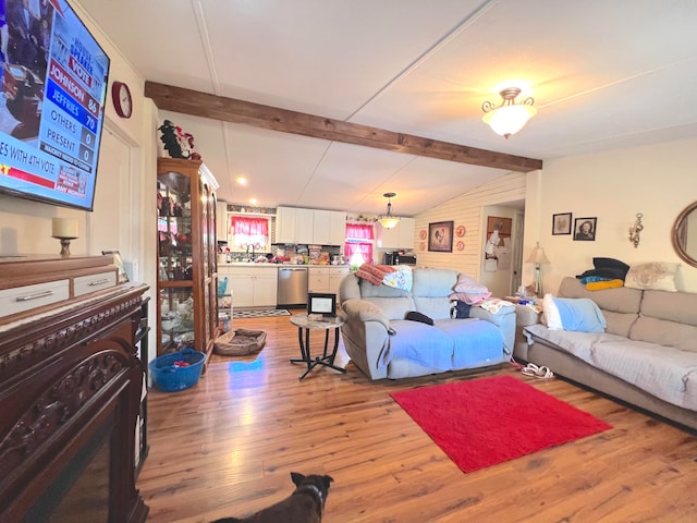 living room with vaulted ceiling with beams and light hardwood / wood-style flooring