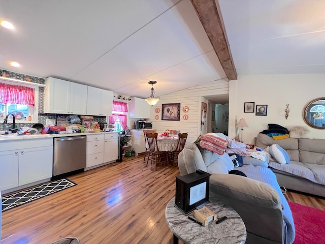 living room featuring lofted ceiling with beams, light hardwood / wood-style floors, and sink