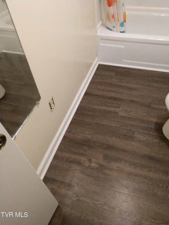 details featuring wood-type flooring, toilet, and shower / bath combination with curtain