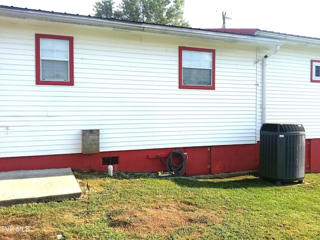 view of side of property with cooling unit and a lawn