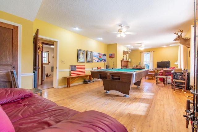 recreation room with a textured ceiling, ceiling fan, pool table, and light hardwood / wood-style flooring