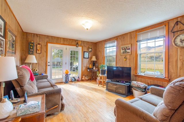 living room featuring wooden walls, a healthy amount of sunlight, and light hardwood / wood-style floors