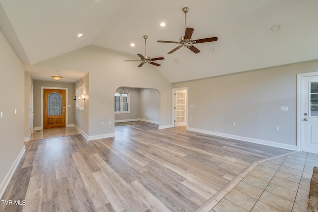 unfurnished living room with high vaulted ceiling, ceiling fan, and light tile flooring