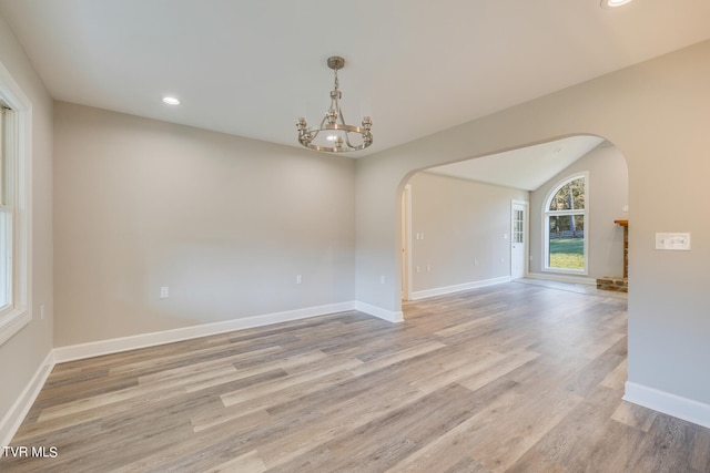 empty room featuring light hardwood / wood-style flooring and a chandelier