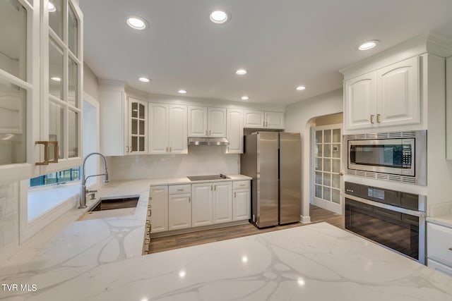 kitchen with stainless steel appliances, wood-type flooring, white cabinets, backsplash, and sink