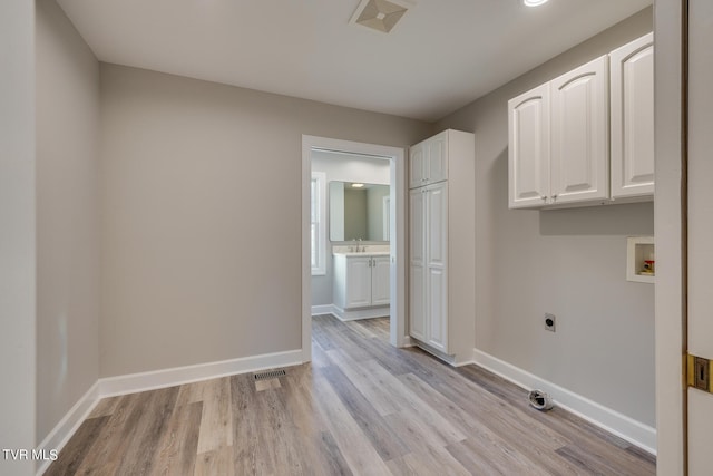 washroom with light hardwood / wood-style flooring, cabinets, electric dryer hookup, and hookup for a washing machine