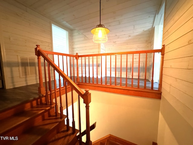 stairway with wood ceiling, visible vents, and wood walls