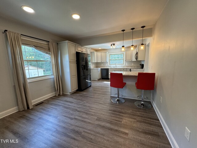 kitchen featuring white cabinetry, sink, hanging light fixtures, a kitchen breakfast bar, and black appliances