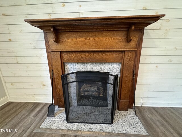 details featuring hardwood / wood-style flooring, a tiled fireplace, and wood walls