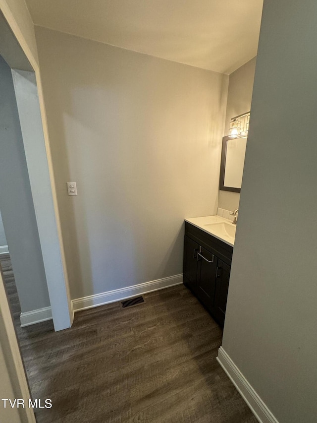 bathroom featuring visible vents, baseboards, wood finished floors, and vanity