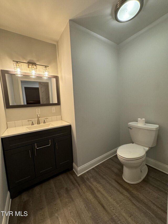 bathroom with toilet, vanity, and hardwood / wood-style flooring