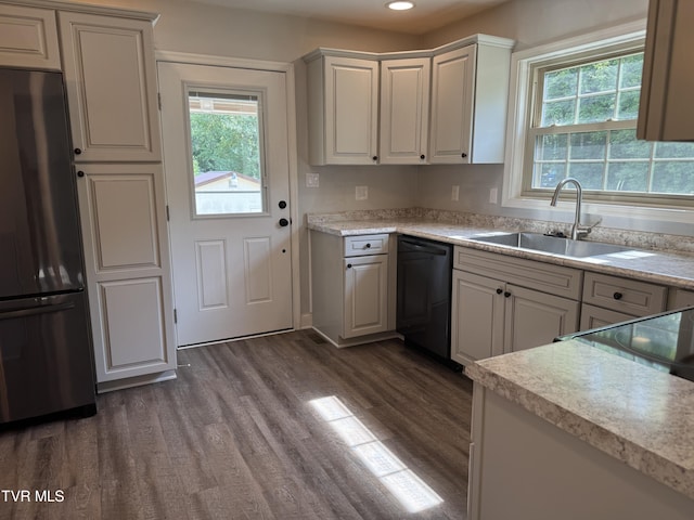 kitchen with freestanding refrigerator, a sink, dark wood-type flooring, light countertops, and black dishwasher