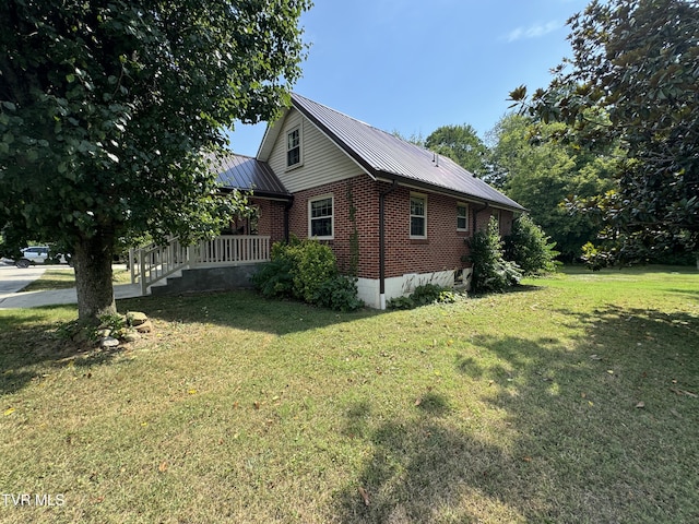 view of side of home featuring metal roof, brick siding, and a lawn