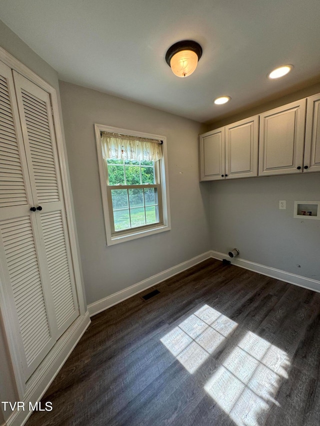 washroom featuring dark hardwood / wood-style flooring, hookup for a washing machine, and cabinets