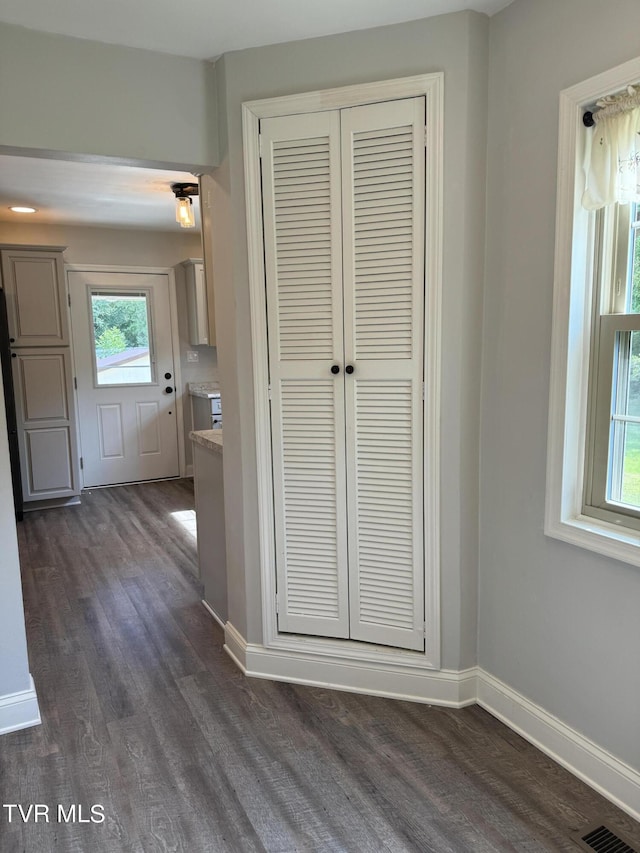 corridor with visible vents, baseboards, and dark wood-style flooring