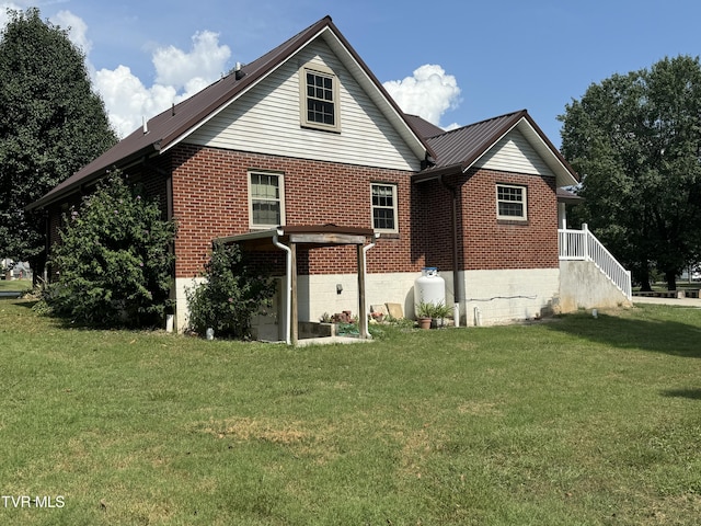 rear view of house featuring brick siding and a lawn