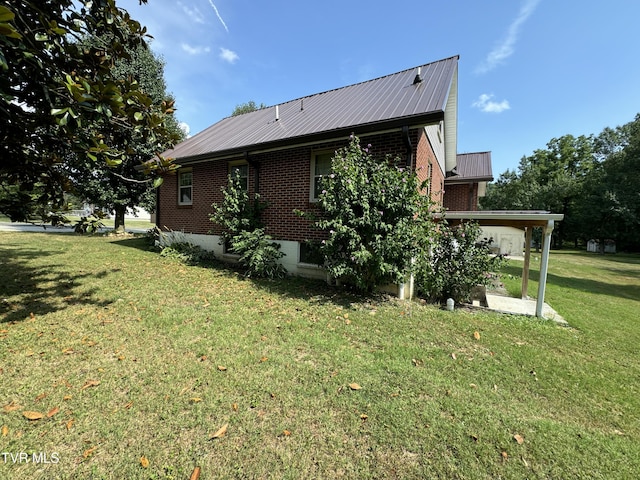 view of side of home with brick siding, a lawn, and metal roof