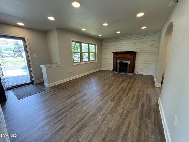 unfurnished living room with dark hardwood / wood-style flooring and wooden walls