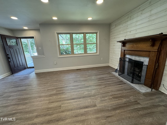 unfurnished living room featuring recessed lighting, a large fireplace, baseboards, and dark wood-style flooring