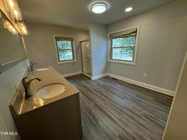 bathroom with a shower stall, wood finished floors, baseboards, and a sink